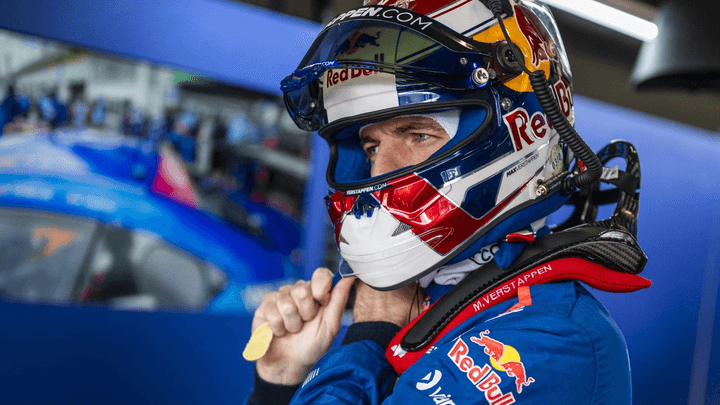 Pilote Red Bull Racing ajustant son casque dans les stands, combinaison bleue aux couleurs de l'équipe