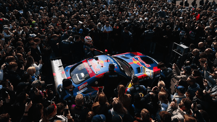 Foule de fans entourant une monoplace F1 Red Bull dans les tribunes d'un circuit