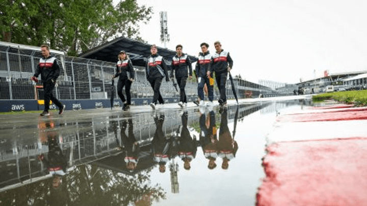 Pilotes de F1 marchant sous la pluie sur une piste mouillée avec reflets