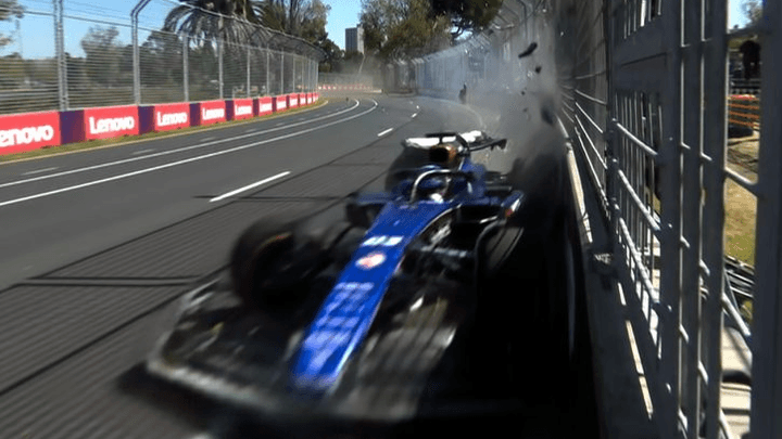 Monoplace de F1 bleue en difficulté avec fumée sur circuit urbain bordé de barrières