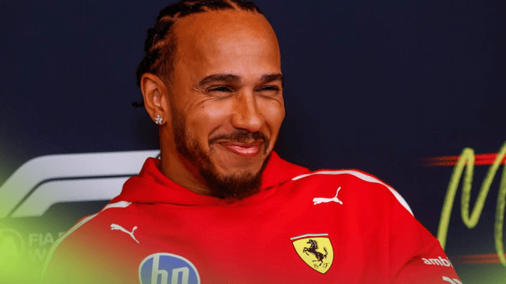 Lewis Hamilton souriant en combinaison Ferrari rouge lors d'une conférence de presse