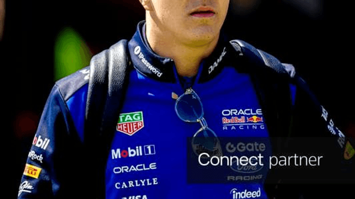 Isack Hadjar en combinaison Red Bull Racing, casquette bleue, regard déterminé
