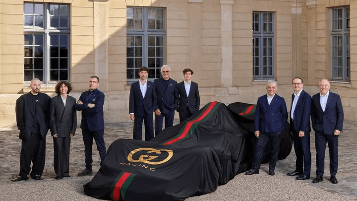 Présentation d'une voiture de F1 voilée avec dirigeants devant un bâtiment officiel