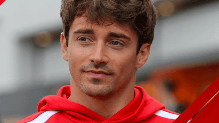 Charles Leclerc en combinaison Ferrari rouge avec le logo de l'écurie, souriant après l'annonce de son nouveau contrat