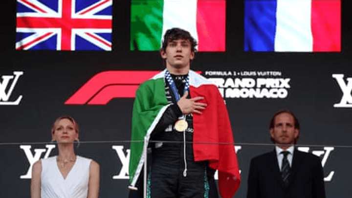 Leclerc sur le podium de Monaco, drapeau italien sur les épaules, hymne national