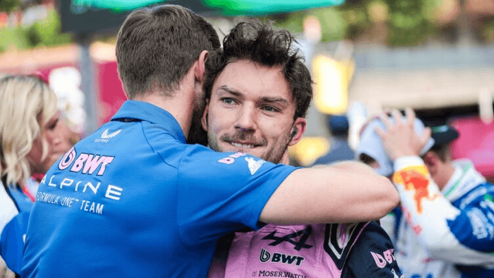 Pilote Alpine F1 embrassant un membre de l'équipe après une course, combinaison rose BWT